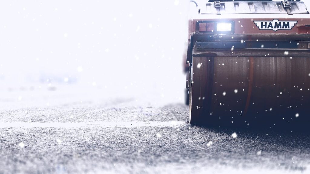 pexels-photo-302686 Close-up of a road roller working on an icy highway during heavy snowfall.